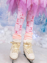 Pink Barbie-themed tights with pink ballet shoes and the word 'Barbie' printed on them, worn by a model in a snowy, icy outdoor setting with white ice skates.